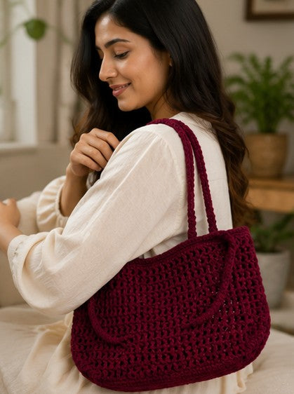 Woman happily adjusting her Handmade burgundy crochet shoulder bag with minimalist woven design for everyday use.