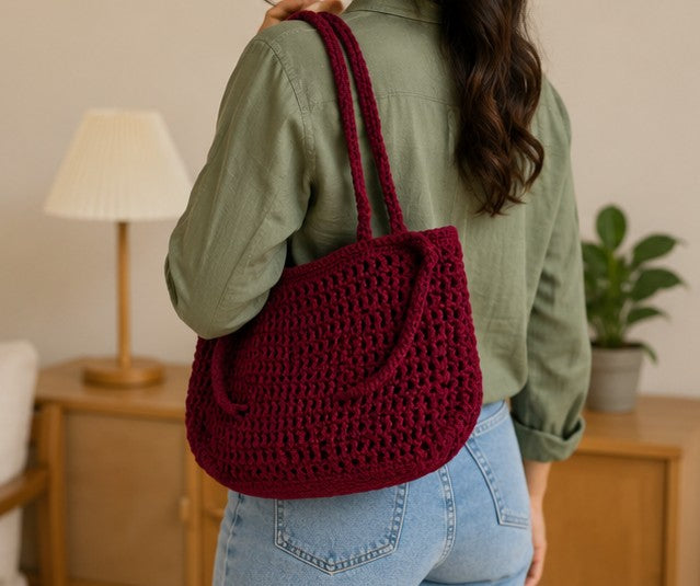 Backshot of woman carrying Handmade burgundy crochet shoulder bag with minimalist woven design for everyday use on her shoulder.